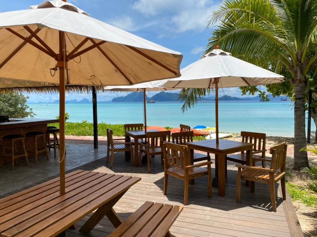 um restaurante com mesas e guarda-sóis na praia em Mali Kradan em Koh Kradan