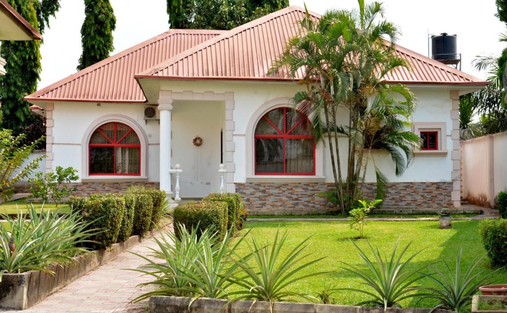 2 Bedroom Bungalow in Alalubosa GRA في إيبادان: منزل بسقف احمر وساحة خضراء