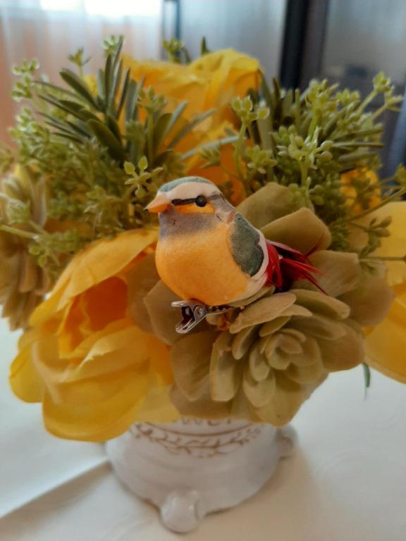 a bird sitting on top of a vase with flowers at Luny apartment in Ruse