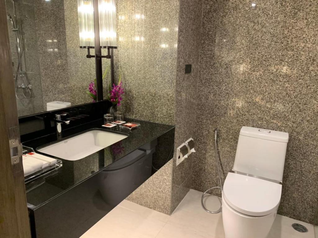 a bathroom with a sink and a toilet and a mirror at Sima Thani Hotel in Nakhon Ratchasima