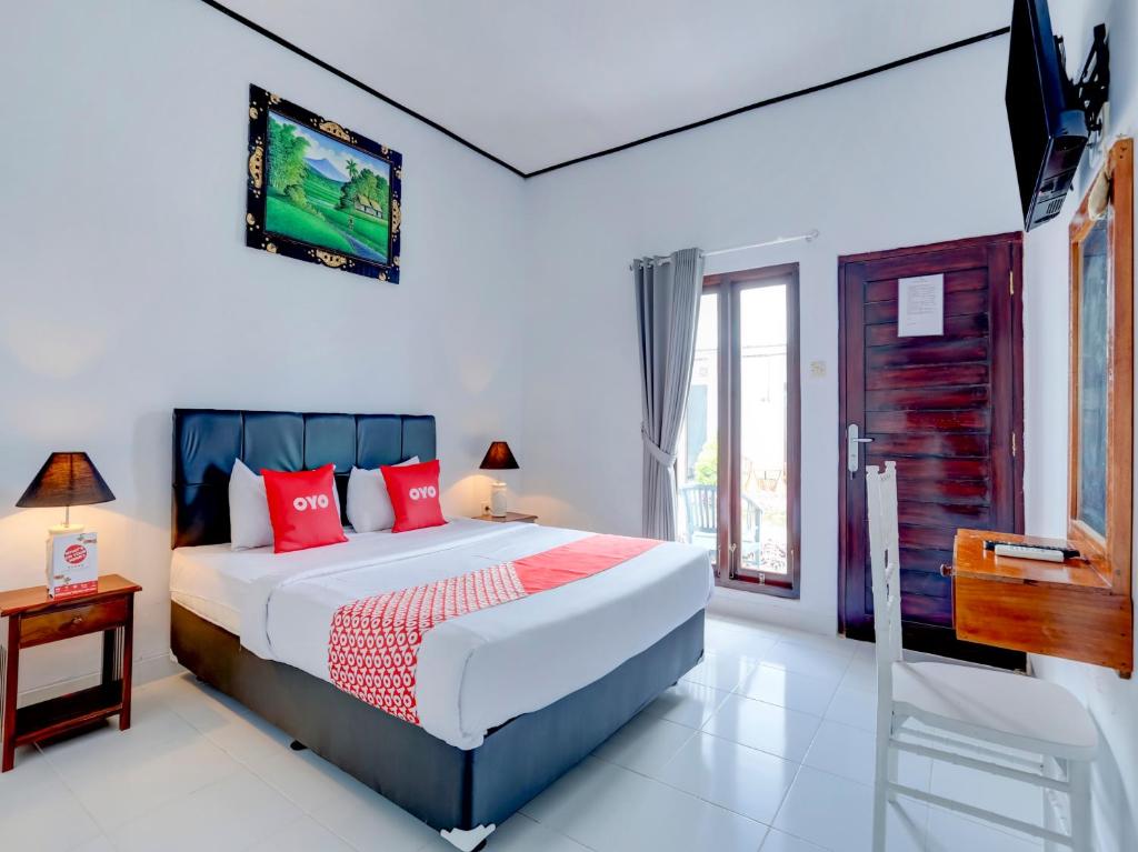 een slaapkamer met een bed en een tv aan de muur bij Bahtera Guest House in Denpasar