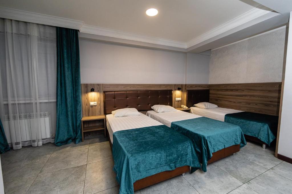 Cette chambre d'hôtel comprend 2 lits avec des draps verts. dans l'établissement Krepost Mini Hotel, à Makhachkala