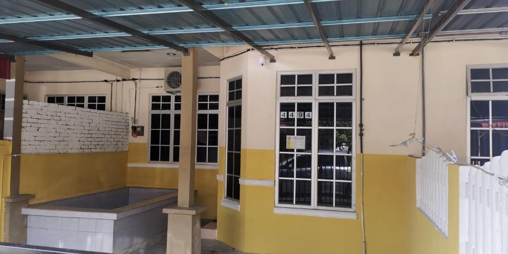 ein Gebäude mit gelben und weißen Wänden und Fenstern in der Unterkunft Aqiza Home Kuala Krai in Kuala Kerai