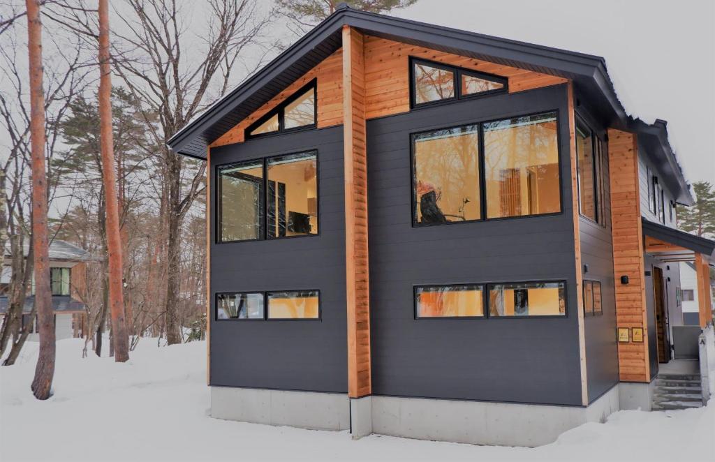 a house with a black exterior in the snow at Snowlines Apartments Hakuba in Hakuba