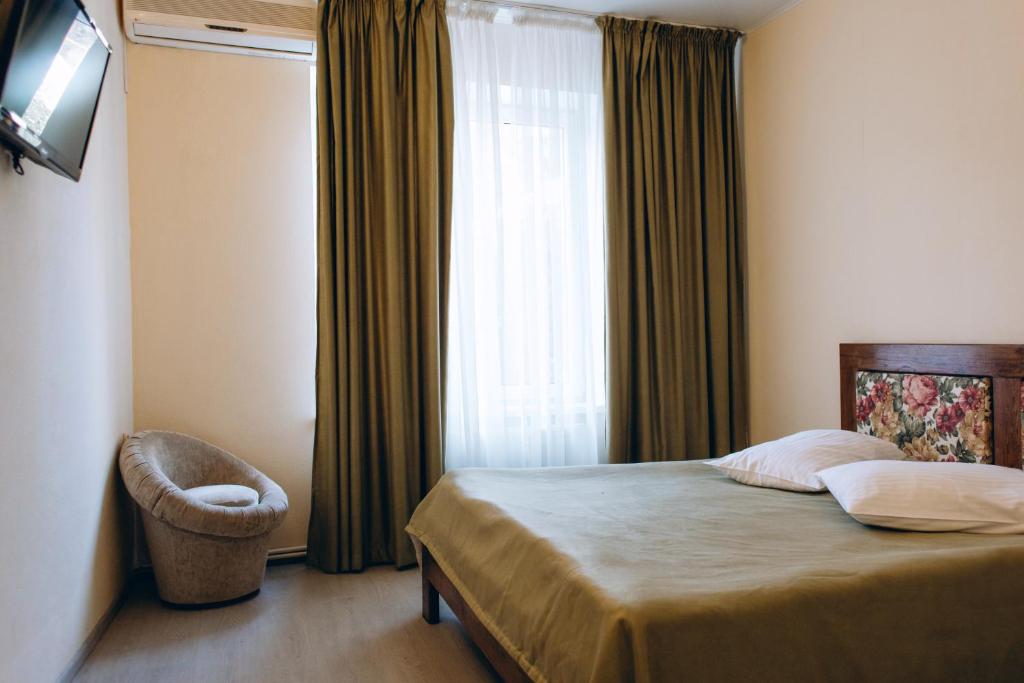um quarto com uma cama e uma janela com uma cadeira em Hotel DA NONNA em Odessa