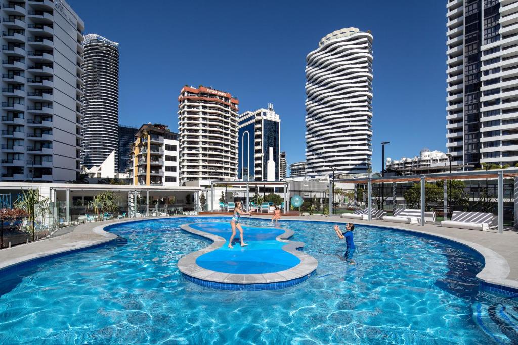 a large swimming pool with two people in a city at ULTIQA Beach Haven on Broadbeach in Gold Coast