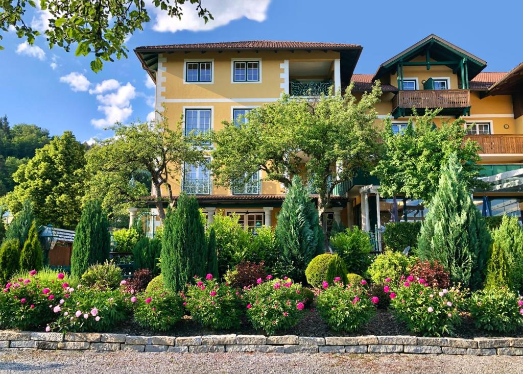 einen Garten vor einem Gebäude mit Blumen in der Unterkunft Gasthaus Hotel Höhenwirt in Keutschach am See