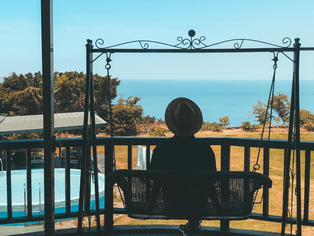 a person sitting on a swing looking out at the ocean at Happiness Ocean View B&B in Xiaoliuqiu