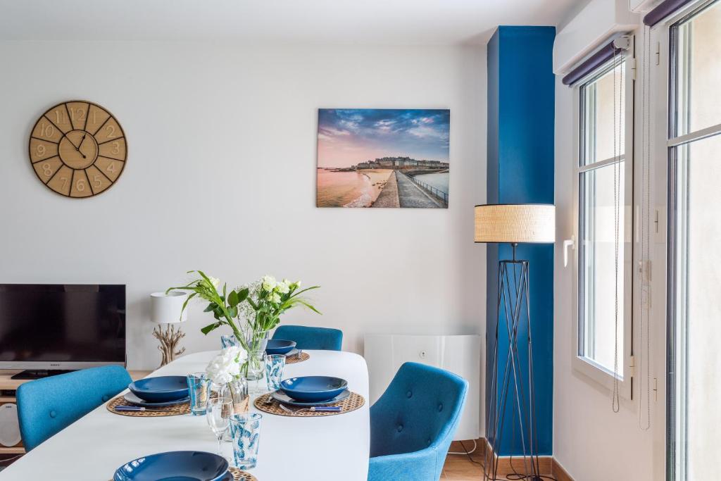 une salle à manger avec une table blanche et des chaises bleues dans l'établissement L'Echo des Vagues, à Saint-Malo