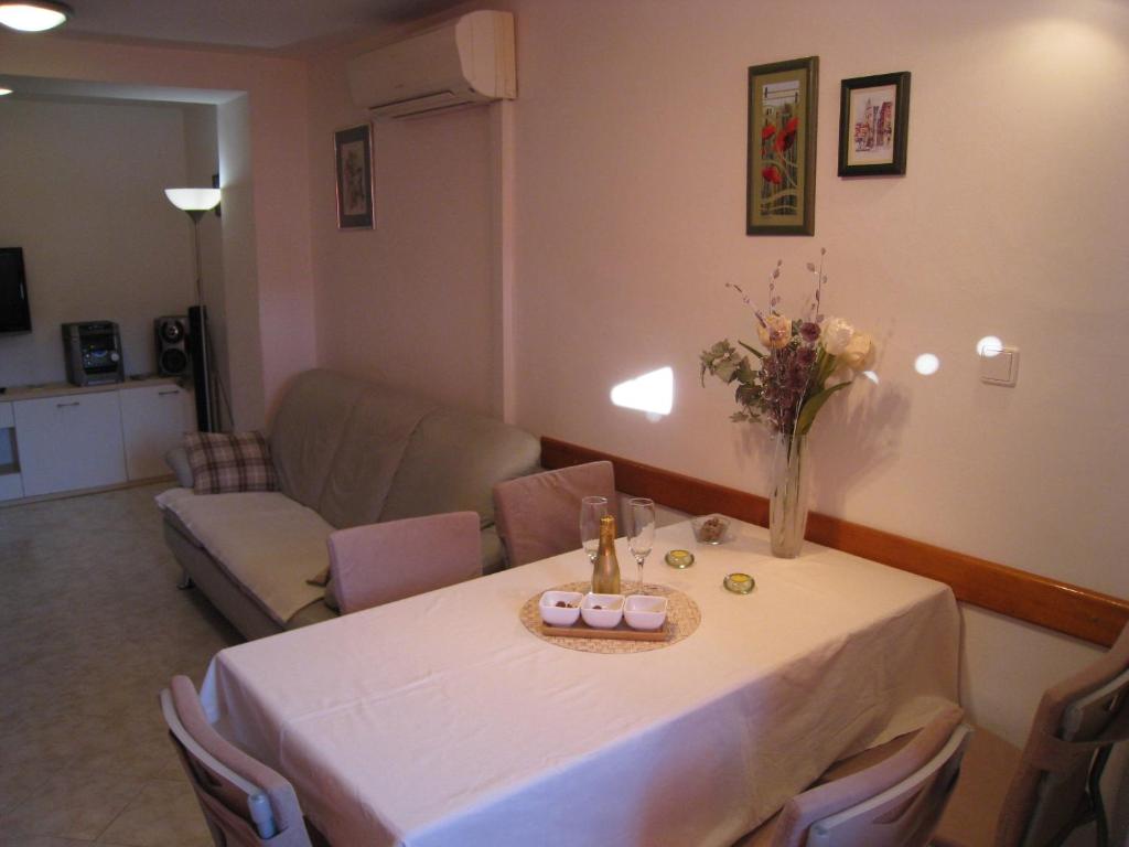 una sala de estar con una mesa con un jarrón de flores. en Apartment Ella Mare, en Zadar