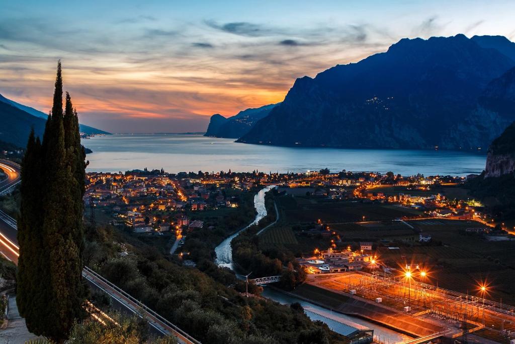 uma vista para uma cidade à noite com montanhas em Hotel Isola Verde em Nago-Torbole