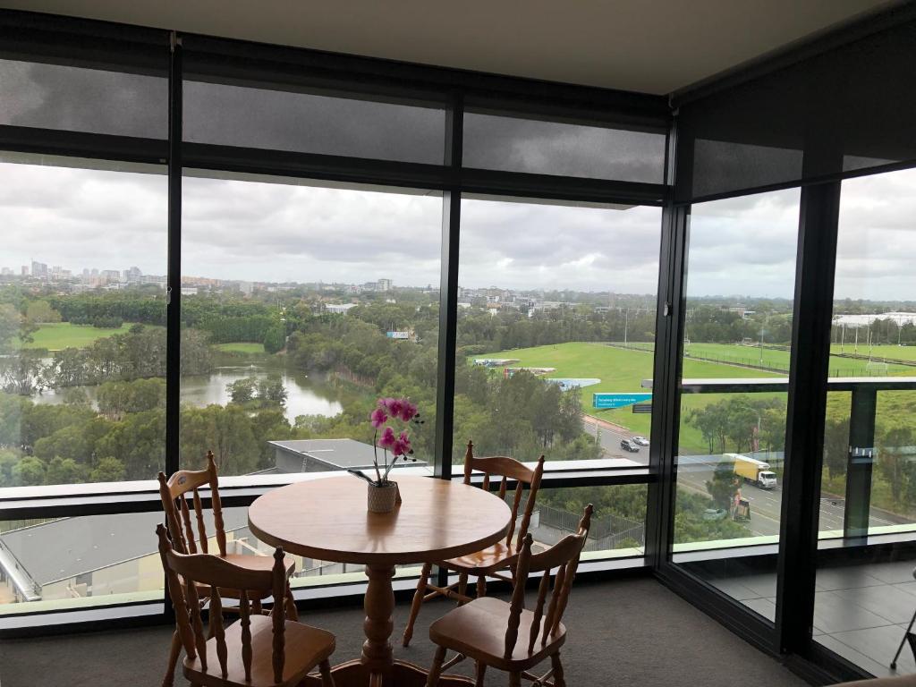 a table and chairs in a room with large windows at Parkview Modern Apartment w Parking @ Olympic Park in Sydney