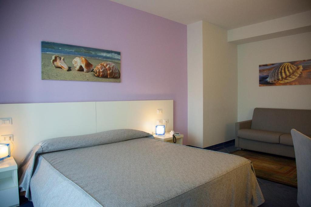 a bedroom with a bed and a chair and a couch at Aurea Hotel in Tortoreto Lido