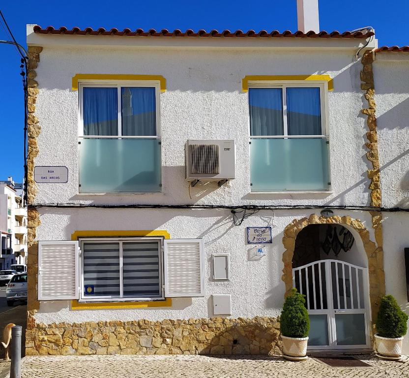 uma casa branca com duas janelas e uma ventoinha em Casa Da Praia "AL" em Monte Gordo