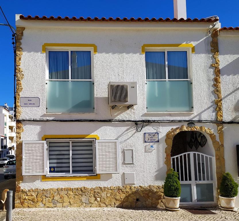 ein weißes Haus mit 2 Fenstern und einem Ventilator in der Unterkunft Casa Da Praia "AL" in Monte Gordo