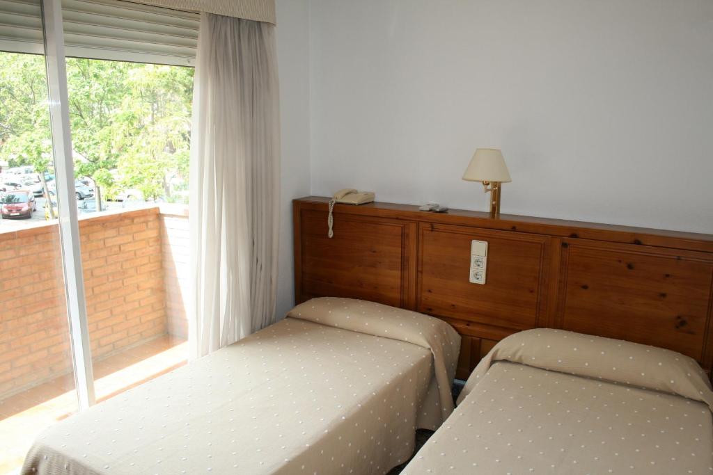 um quarto com 2 camas individuais e uma janela em Hostal Puente de Piedra em Saragoça