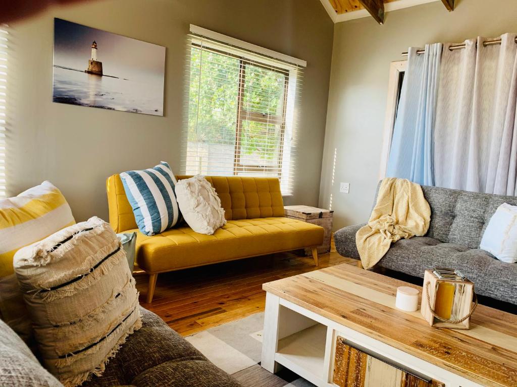 a living room with a yellow couch and a table at Cabins Sodwana Bay - antibootika in Sodwana Bay