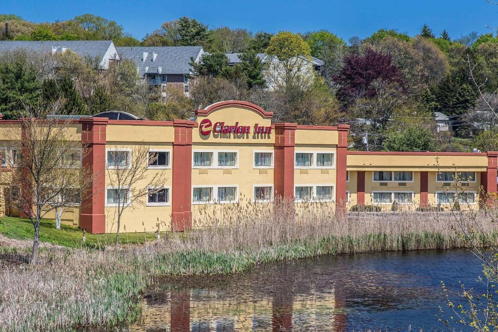 a building with a sign on it next to a river at Clarion Inn New London - Mystic in New London