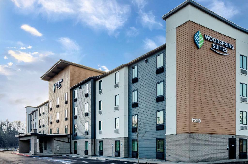 un grand bâtiment avec un panneau sur son côté dans l'établissement WoodSpring Suites Tacoma - Lakewood, à Lakewood