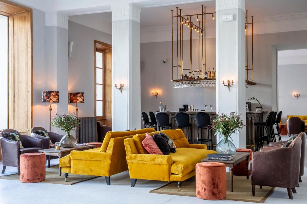 a living room with a yellow couch and tables at Langley Resort Napoléon Bonaparte in LʼÎle-Rousse