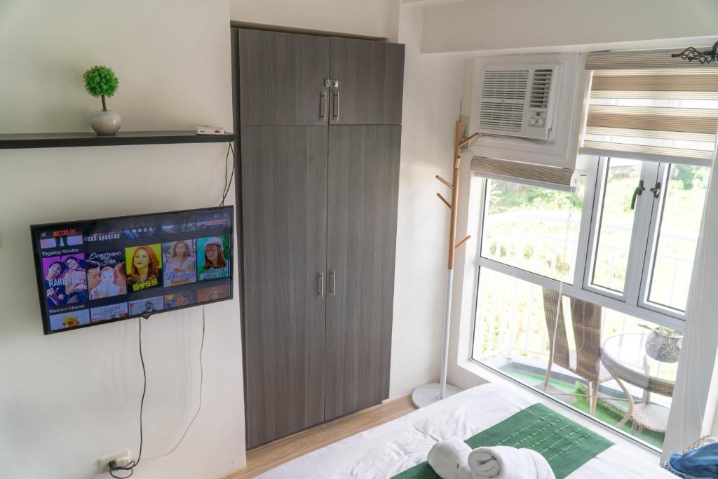 a bedroom with a tv and a bed and a window at An Oasis in Tagaytay in Tagaytay