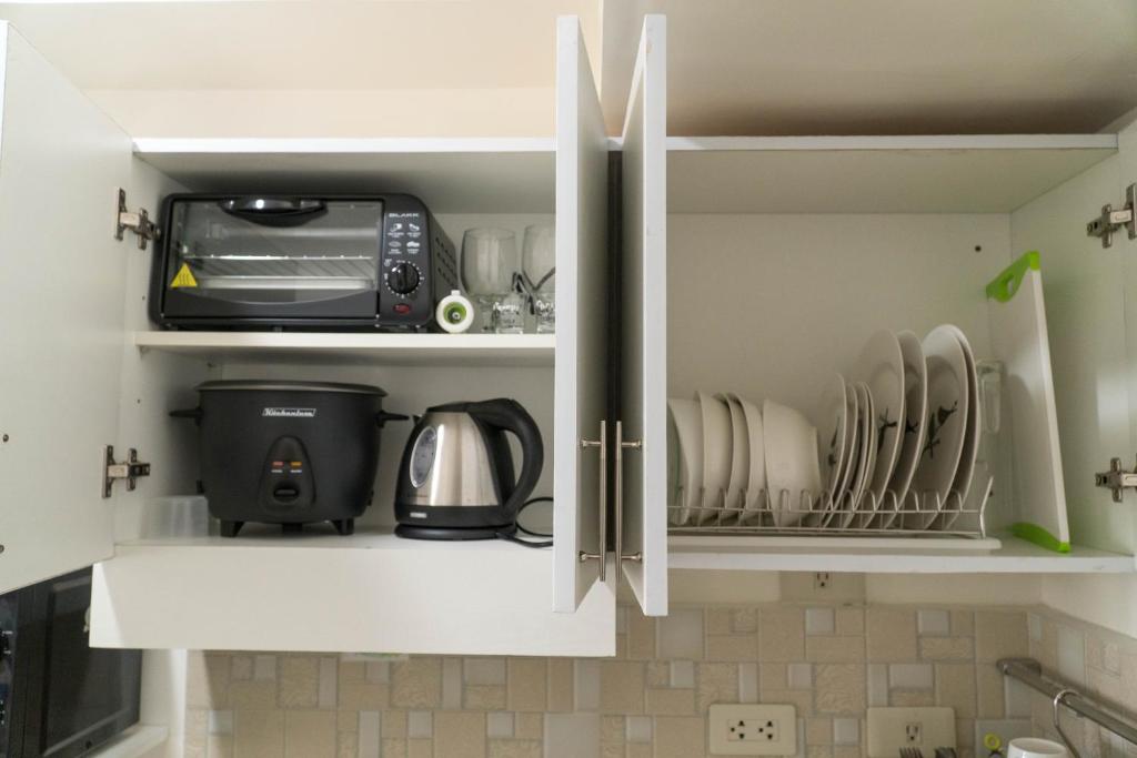 a kitchen cupboard filled with dishes and a microwave at An Oasis in Tagaytay in Tagaytay