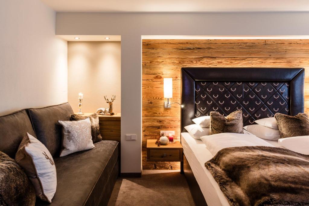 a bedroom with a large bed and a couch at Superior Hotel Panorama in Obertauern