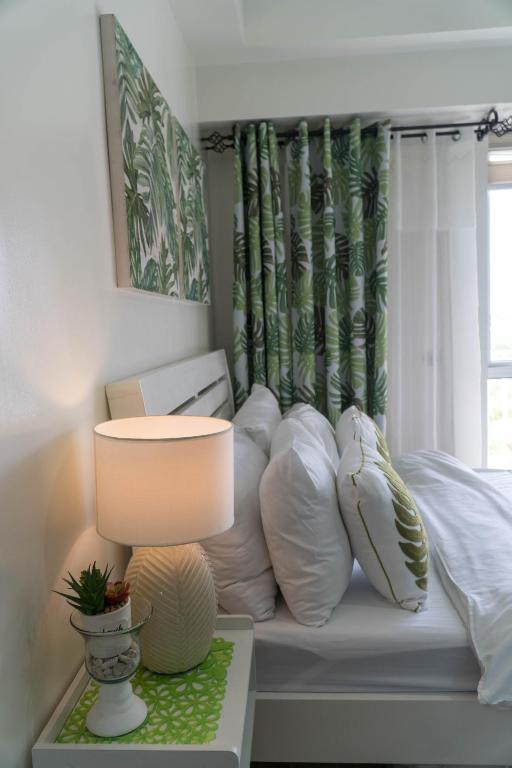 a bedroom with a bed with pillows and a lamp at An Oasis in Tagaytay in Tagaytay