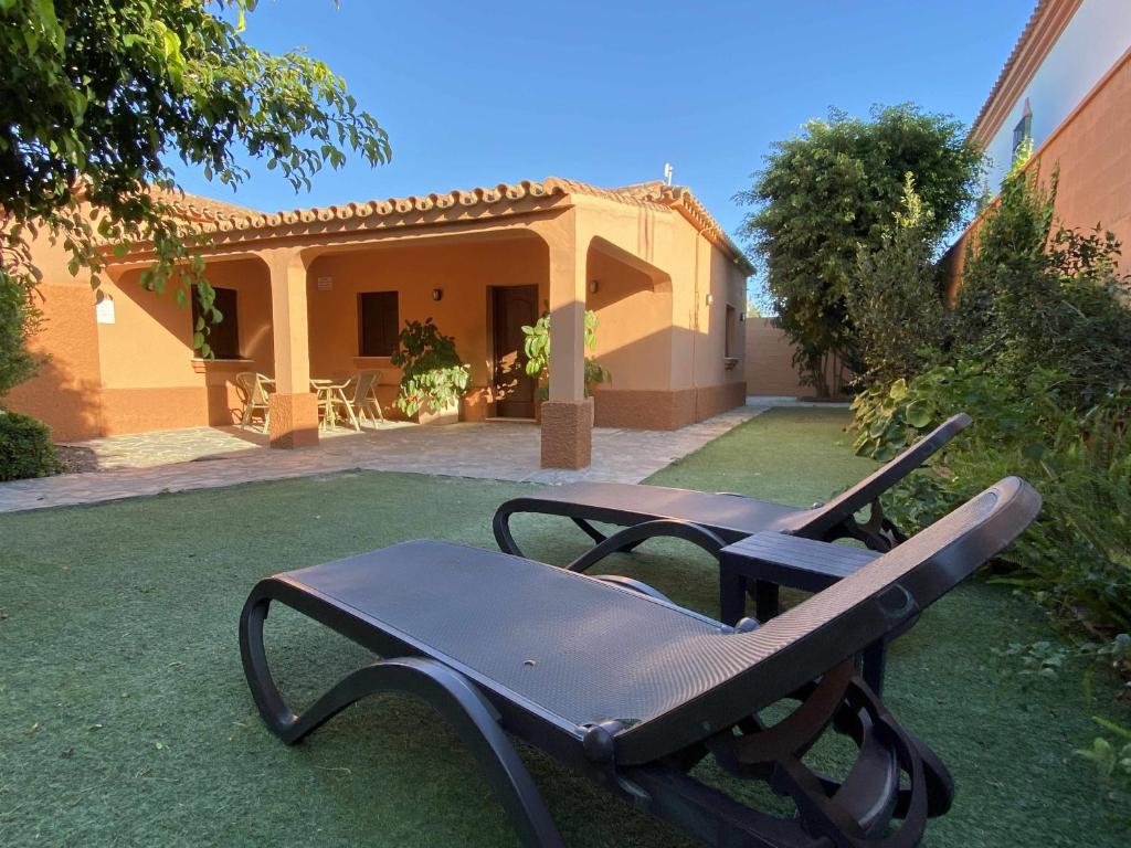 a chair in a yard in front of a house at Casa con jardín privado para hasta 7 personas y piscina compartida in Cádiz