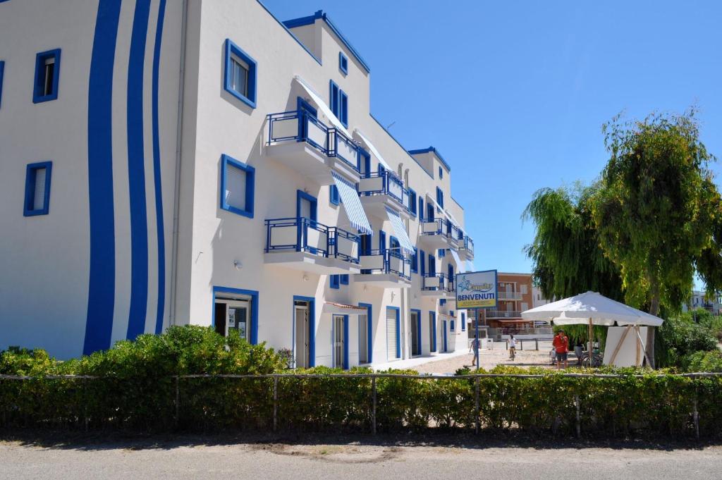 ein großes weißes Gebäude mit blauen Balkonen und einem Sonnenschirm in der Unterkunft Campitur in Campomarino