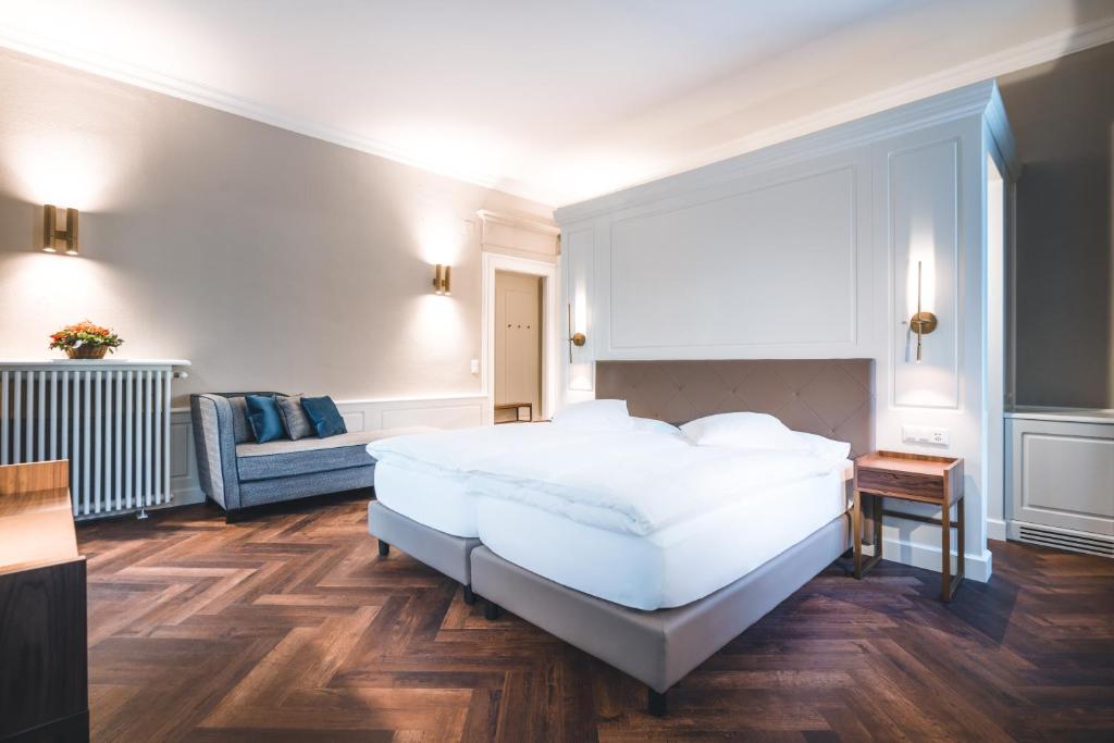 una camera da letto con un letto bianco e un divano di Hotel Reine Victoria a Sankt Moritz