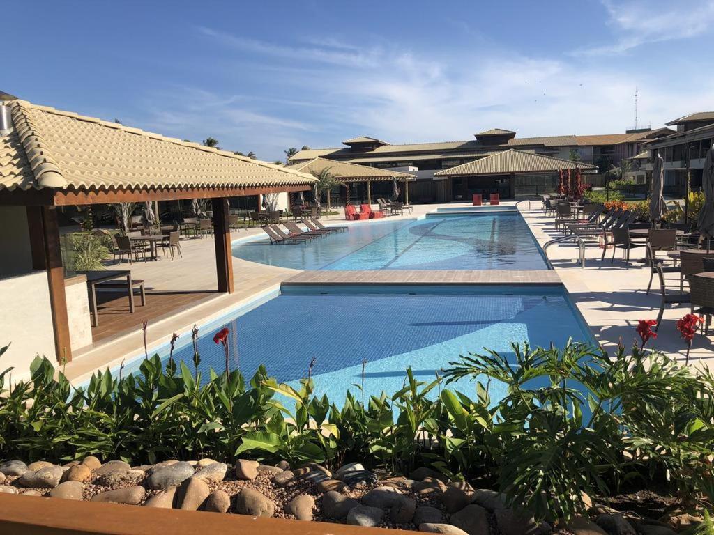 a large swimming pool with tables and chairs at Residencial Ykutiba in Imbassai