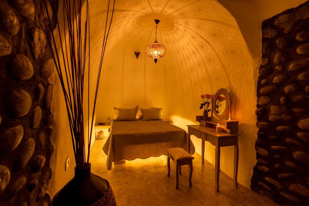 um quarto com uma cama e uma mesa com um candeeiro em BLACK BAY CAVES SUITES em Akrotírion