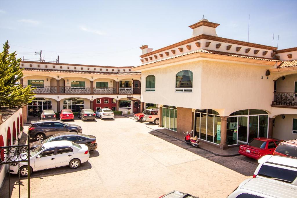 un parking avec des voitures garées devant un bâtiment dans l'établissement HOTEL XILONEN PALACE, à Jilotepec de Abasolo