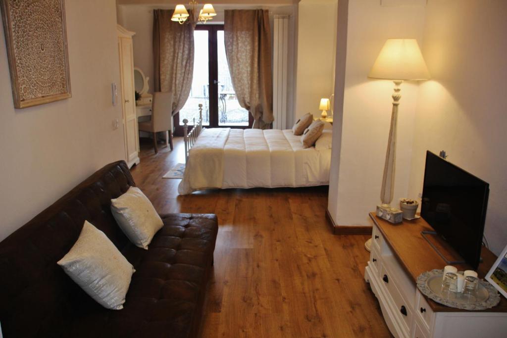 een woonkamer met een bank en een bed bij Maison del Borgo in Colle di Val d'Elsa