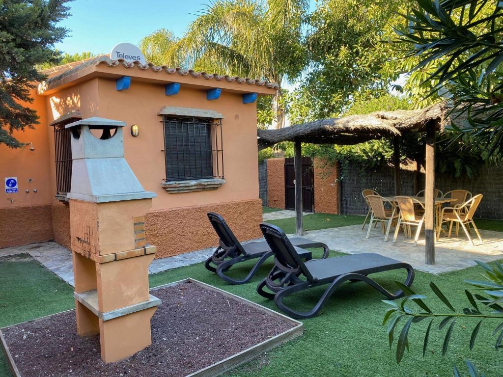 une arrière-cour avec une maison ornithologique, des chaises et une table dans l'établissement Casa Bungalows con jardín privado y piscina compa, à Cadix