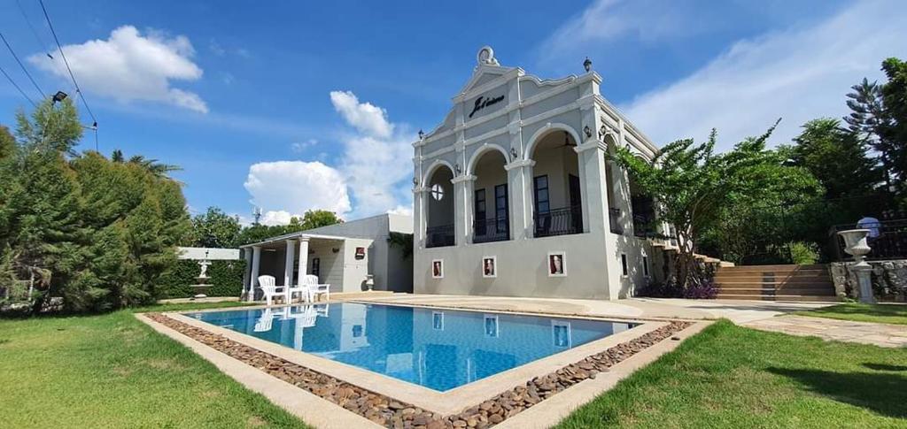 a house with a swimming pool in the yard at Je t'aime cafe & villa in Sing Buri