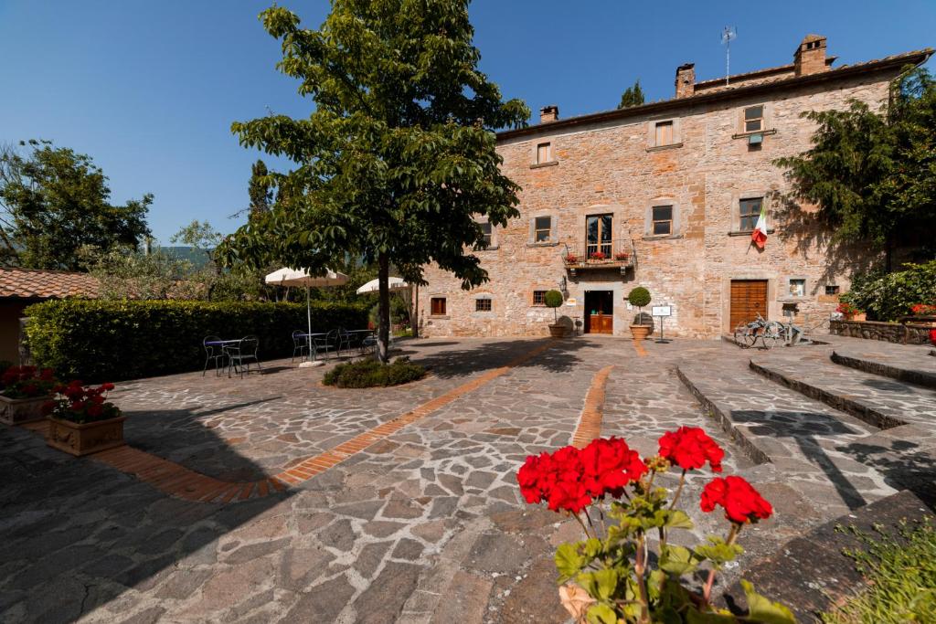 un bâtiment en pierre avec des fleurs rouges devant lui dans l'établissement Relais Parco Fiorito & SPA - Agriturismo, Ristorante e Fattoria Didattica, à Cortone