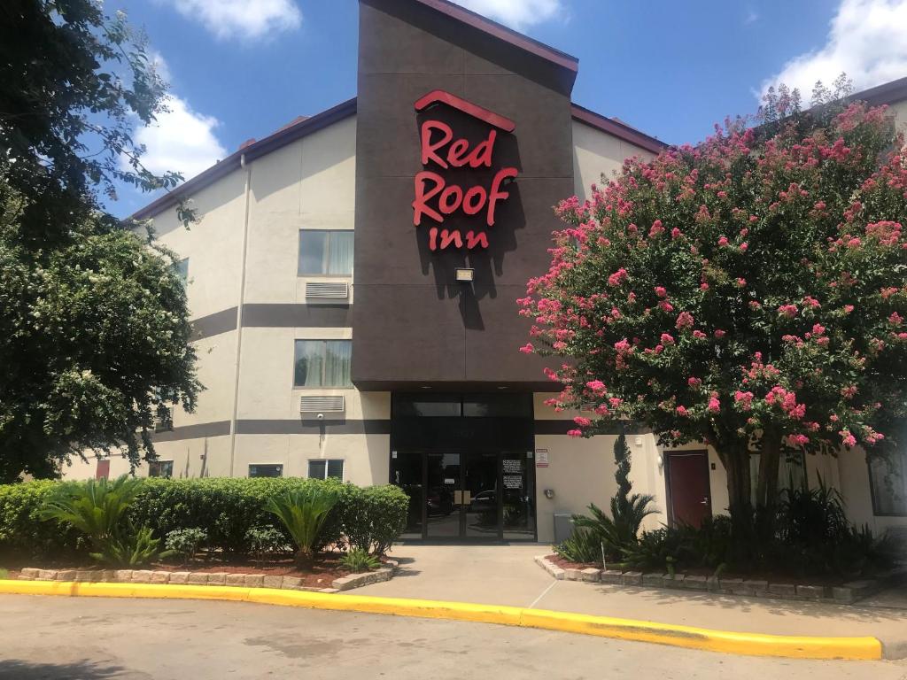 un cartello rosso per la locanda sul lato di un edificio di Red Roof Inn Houston Brookhollow a Houston