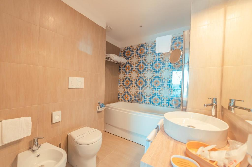 a bathroom with a toilet and a tub and a sink at Hotel Rivage Taormina in Taormina