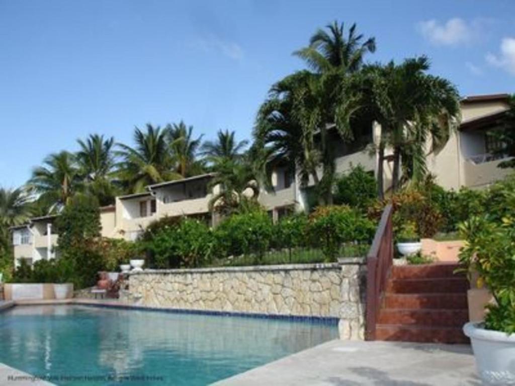 una piscina frente a un edificio con palmeras en Attractive 2-Bed Apartment stunning sea view, en Dickenson Bay