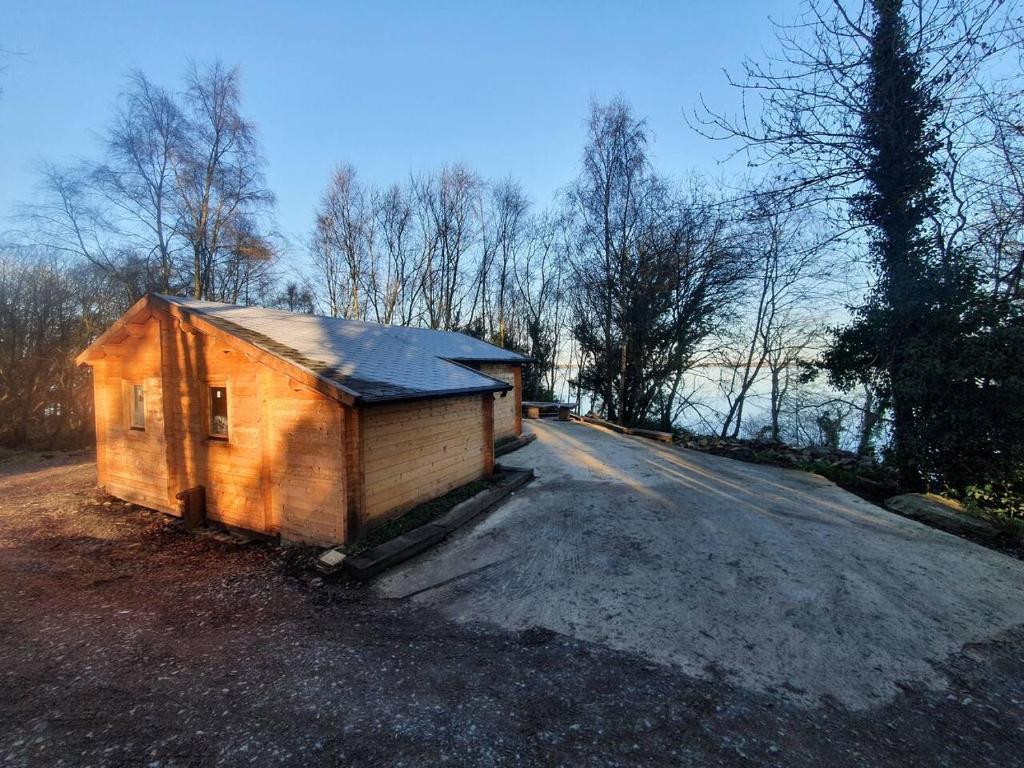 una piccola capanna seduta sul ciglio di una strada di Stunning log cabin on the lake a Portroe