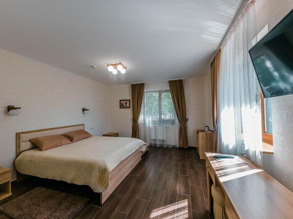 ein Hotelzimmer mit einem Bett und einem Flachbild-TV in der Unterkunft Постріл в Комплексі "Сокіл" in Susk