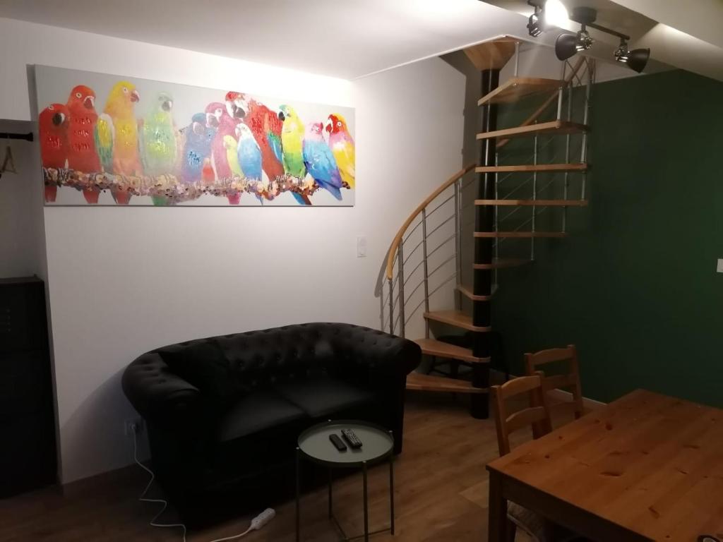 a living room with a chair and a painting of parrots at Le petit Vaudois in Saint-Parres-lès-Vaudes