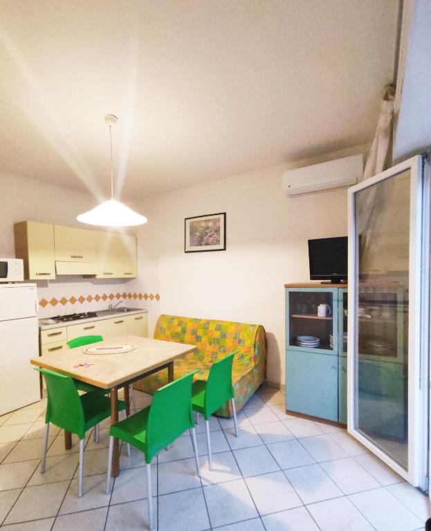 a kitchen and dining room with a table and green chairs at Residence Stella Polare in Bibione