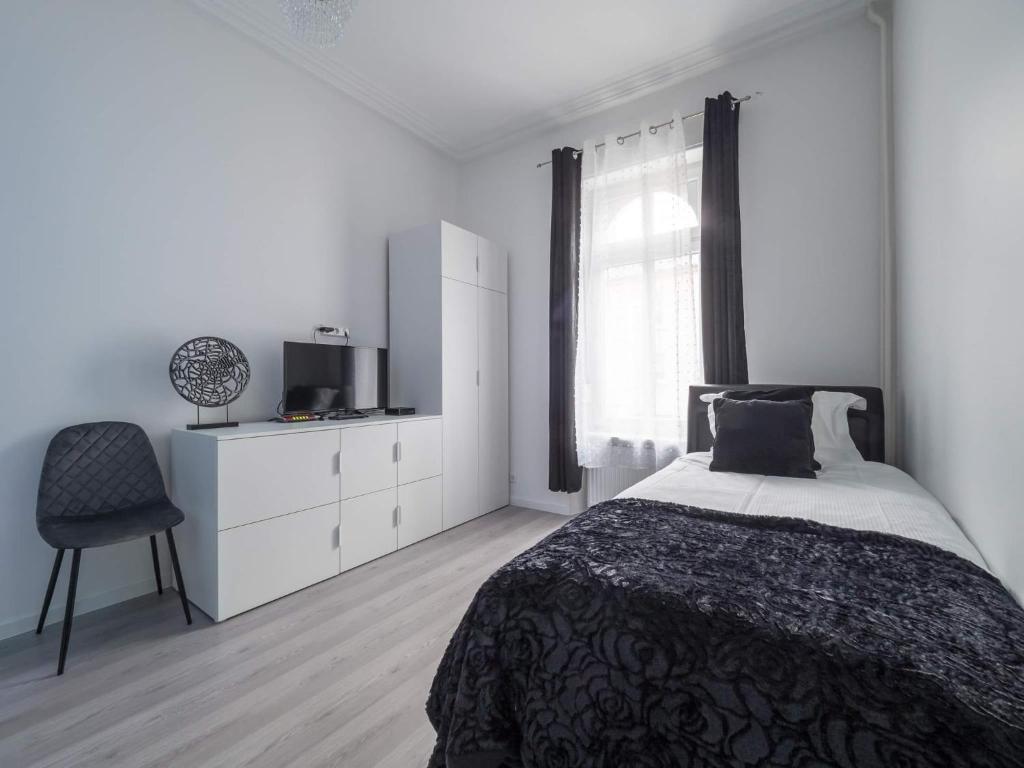 ein weißes Schlafzimmer mit einem Bett und einem Stuhl in der Unterkunft EXECUTIVE SINGLE ROOM WITH EN-SUITE in GUEST HOUSE CITY CENTRE in Luxemburg (Stadt)
