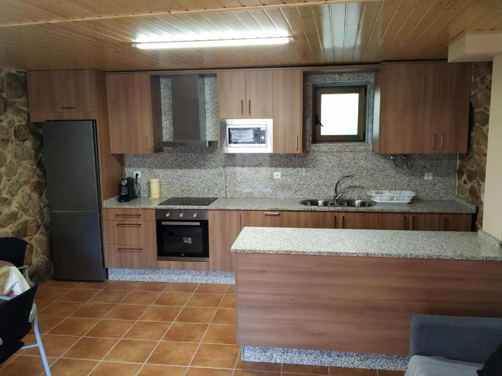 a kitchen with wooden cabinets and a counter top at Casa del Autón - Couto Mixto in Rubiás