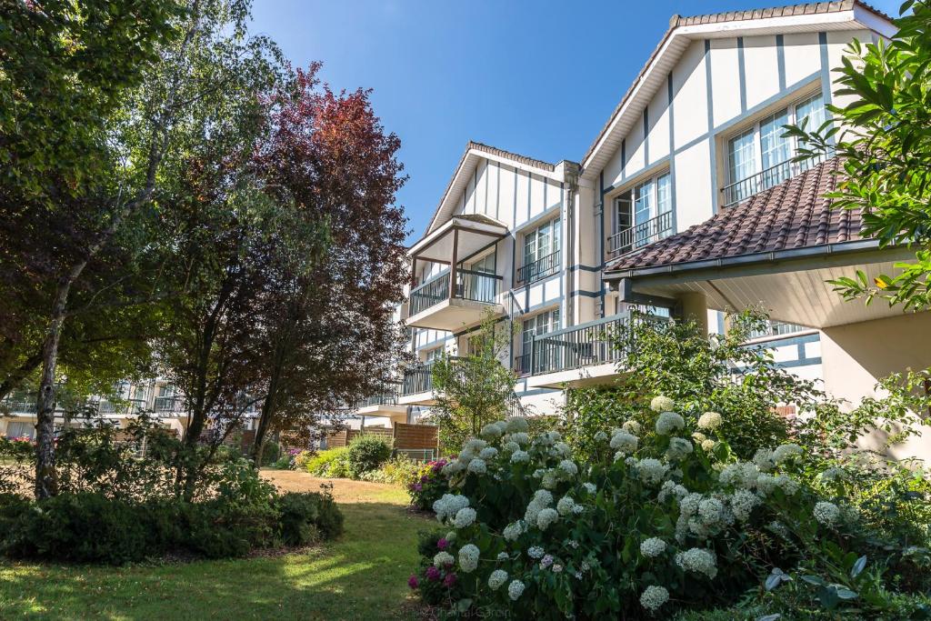 un bâtiment avec un jardin en face dans l'établissement Hôtel du Parc, à Hardelot-Plage