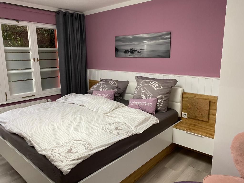 Un dormitorio con paredes moradas y una cama con almohadas. en Ferienzimmer Am Strom 34, en Rostock