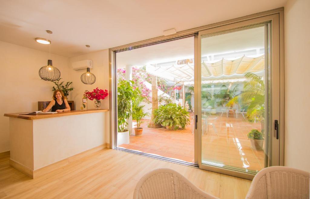 a woman sitting at a desk in front of a glass door at Fortuna in Los Caños de Meca